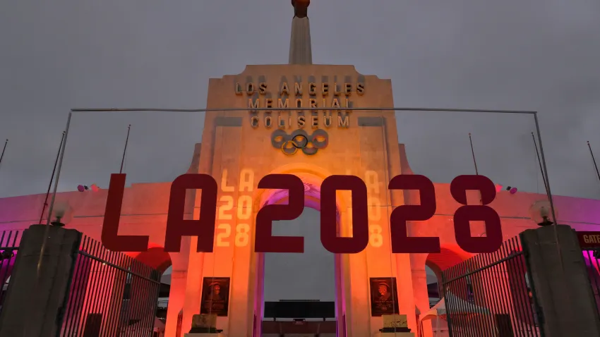 In this Sept. 13, 2017, file photo, an LA 2028 sign is seen in front of a blazing Olympic cauldron at the Los Angeles Memorial Coliseum.