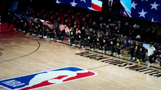 Aug 7, 2020; Lake Buena Vista, Florida, USA; Members of the Toronto Raptors, left, and Boston Celtics listen to the U.S. national anthem prior an NBA basketball game at The Arena. Mandatory Credit: Ashley Landis/Pool Photo-USA TODAY Sports