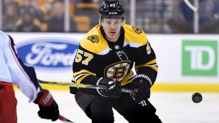 Mar 19, 2018; Boston, MA, USA; Boston Bruins center Tommy Wingels (57) flips the puck past Columbus Blue Jackets defenseman Markus Nutivaara (65) during the first period at TD Garden. Mandatory Credit: Bob DeChiara-USA TODAY Sports