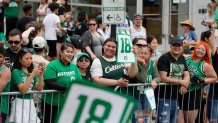 Fans hold signs in Copley Square along the route of the parade.