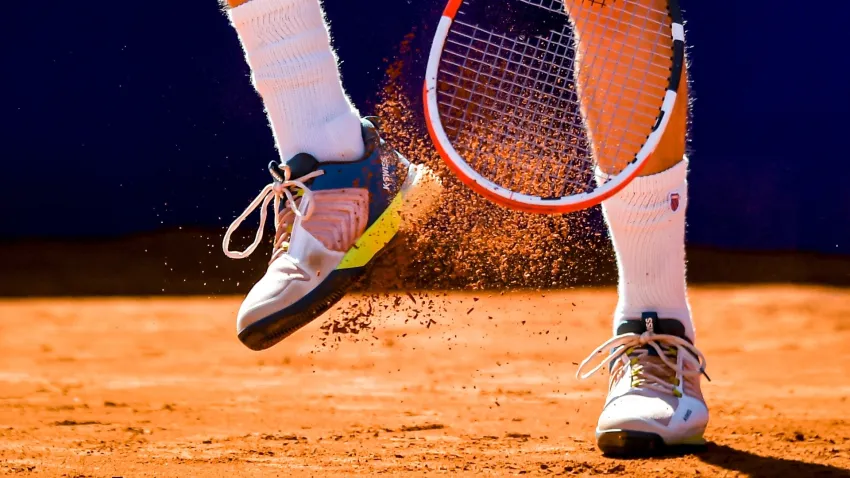 Clay falls off the shoe of a tennis player.