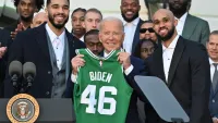 President Joe Biden holds up a Boston Celtics jersey with his name on it while flanked by Jayson Tatum, Derrick White and the rest of the 2024 NBA champions during a ceremony at the White House on Thursday, Nov. 21, 2024.