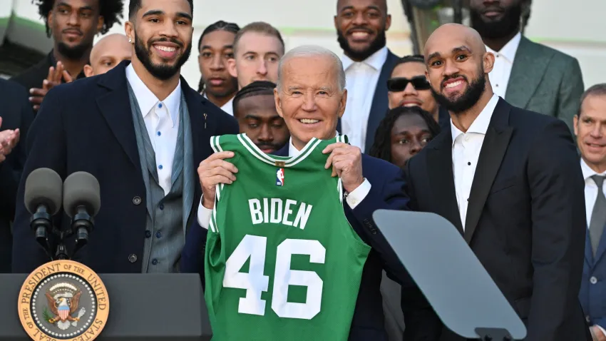 President Joe Biden holds up a Boston Celtics jersey with his name on it while flanked by Jayson Tatum, Derrick White and the rest of the 2024 NBA champions during a ceremony at the White House on Thursday, Nov. 21, 2024.